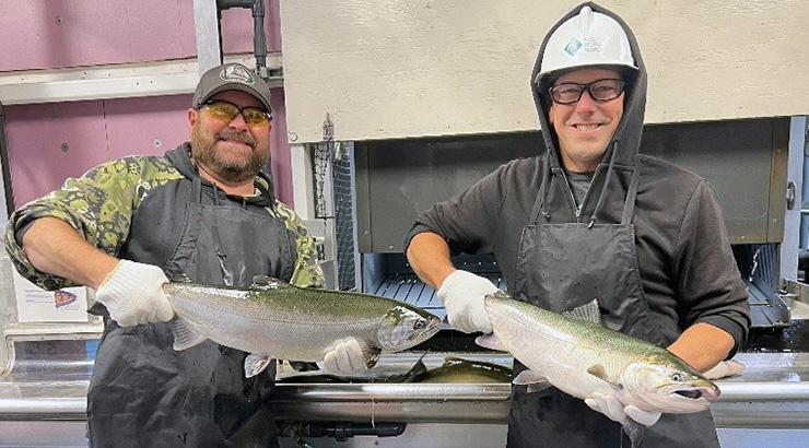 Two men display migrating fish for trap-and-haul program