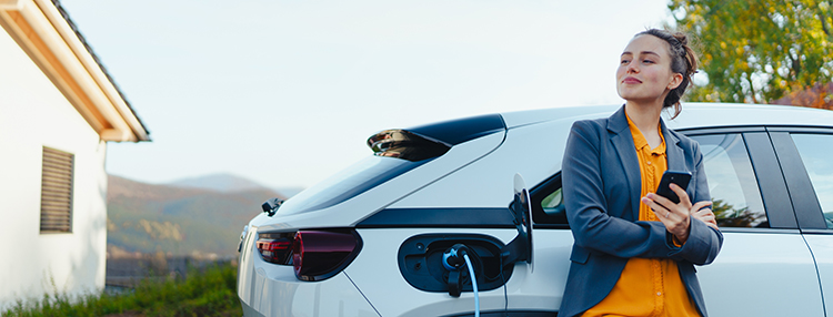 Person holding a phone next to an Electric Vehicle.