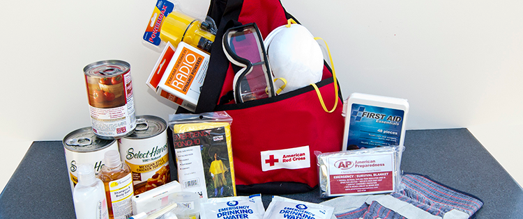 A red backpac with packaged food and water, safety glasses, dust mask, and first aid supplies.