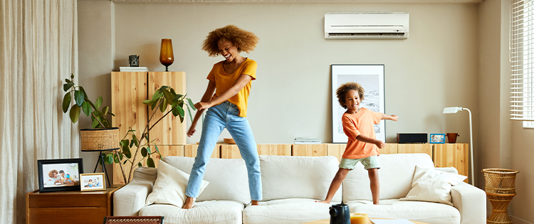 Increase your tenants’ satisfaction - Woman and child dancing on beige couch 