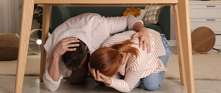 Couple taking cover under a table during an earthquake