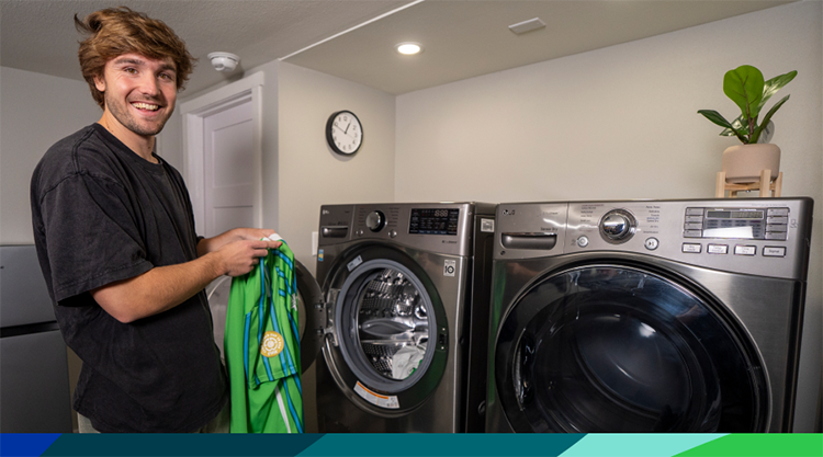 Professional soccer player Pedro de la Vega of Seattle Sounders FC folds laundry next to washer and dryer.