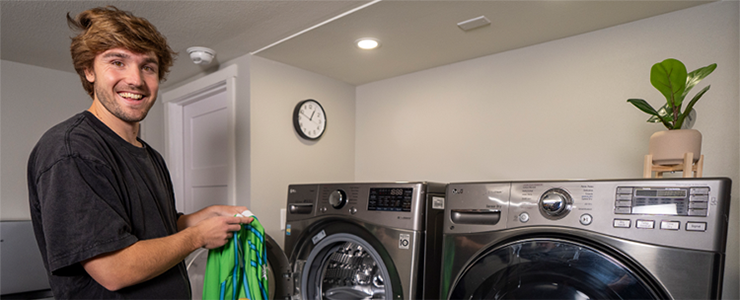 सिएटल साउंडर्स एफसी के पेशेवर फुटबॉल खिलाड़ी पेड्रो डे ला वेगा वॉशर और ड्रायर के बगल में कपड़े धोते हैं।