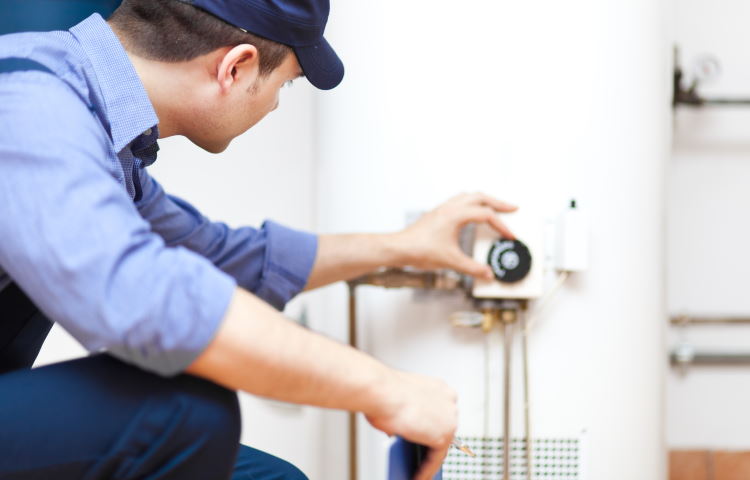 A technician adjusts a dial on a water heater tank.