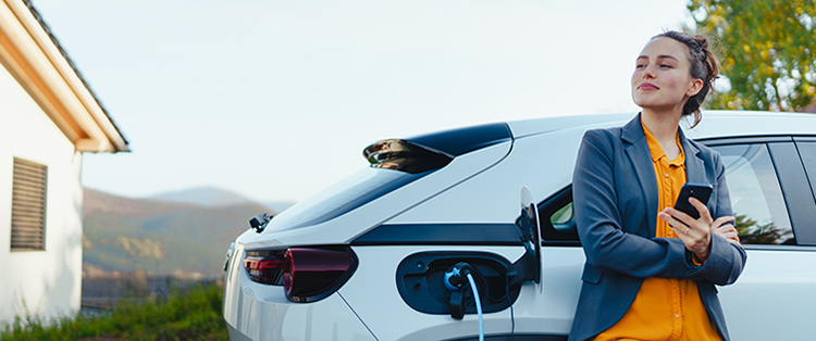 Person holding a phone next to an Electric Vehicle.