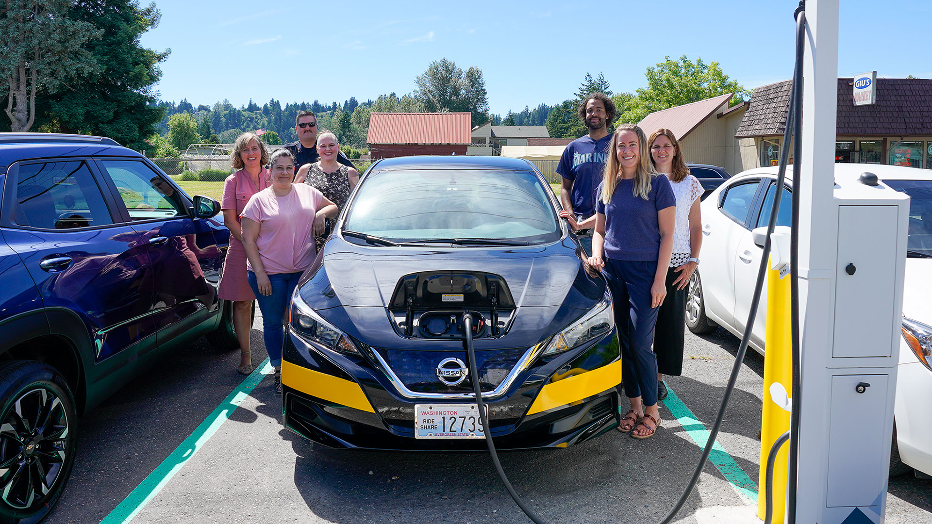 King County Metro and PSE employees pose with a new electric Community Van and charger installed with the help of our Equity Focused pilot.