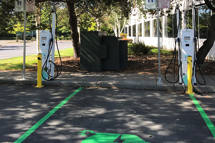Two shaded parking spaces with PSE branded "Up & Go Electric" charging stations.