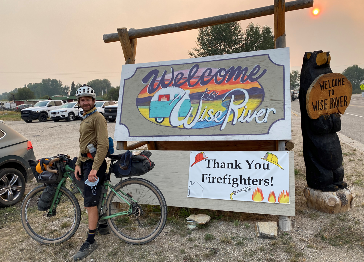 Hunter is shown standing with his bike in front of a sign 