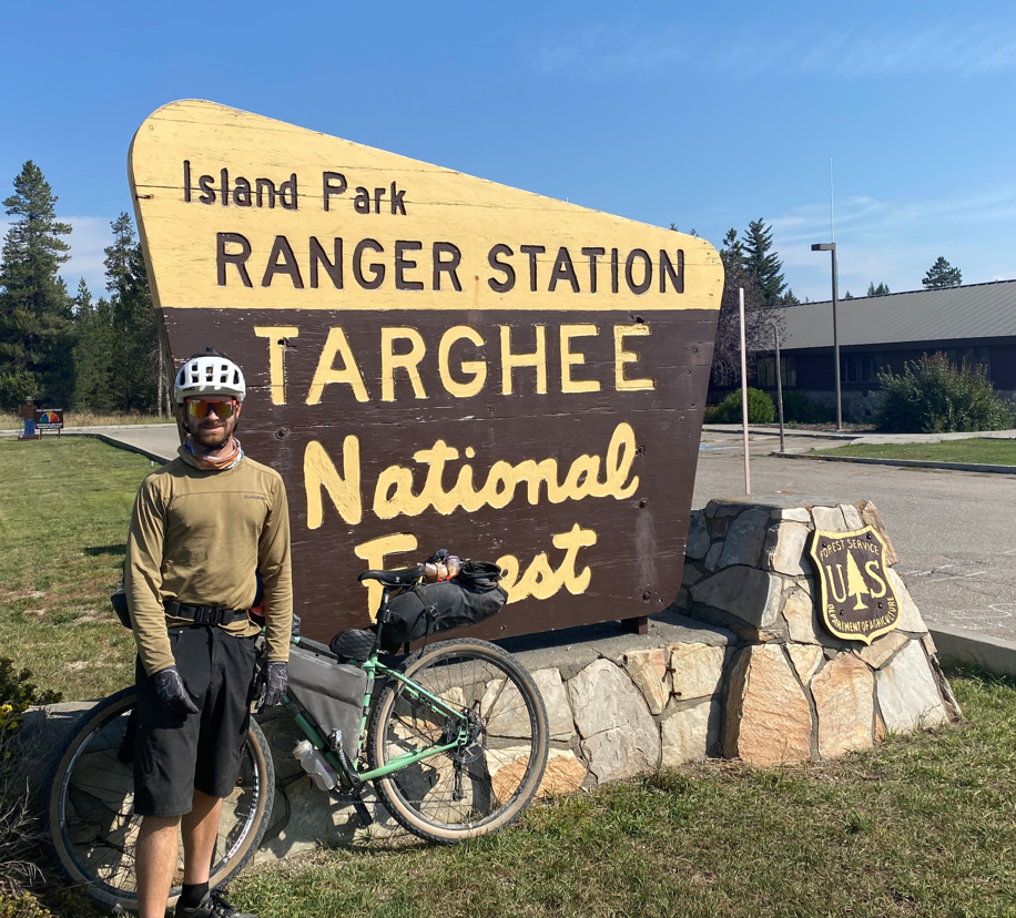 Hunter Hassig is shown standing with his bike in front of a sign