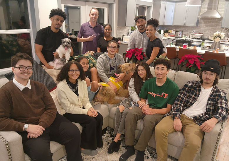 Nicole and her husband, gathered about a v-shaped sectional sofa with 10 smiling family members and two dogs