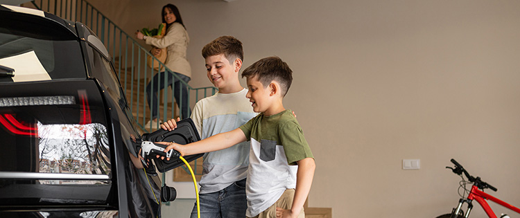Two children charge EV in garage