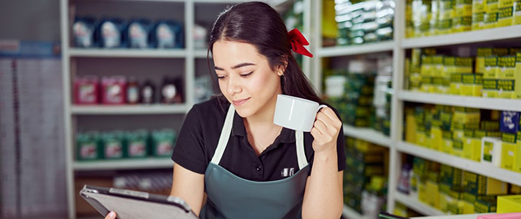 Store clerk reading tablet drinking coffee