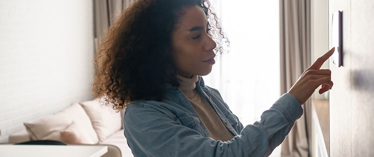 Woman adjusting the thermostat.