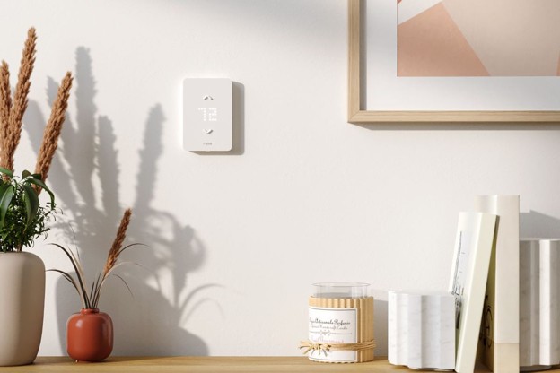 Smart thermostat on a wall above bookcase