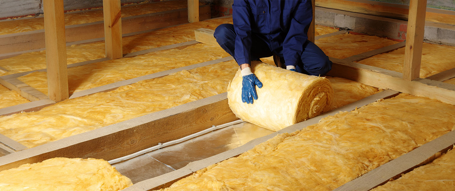 Worker installing insulation roll in attic