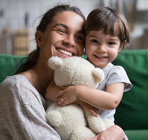 Woman and child hugging a stuffed animal together